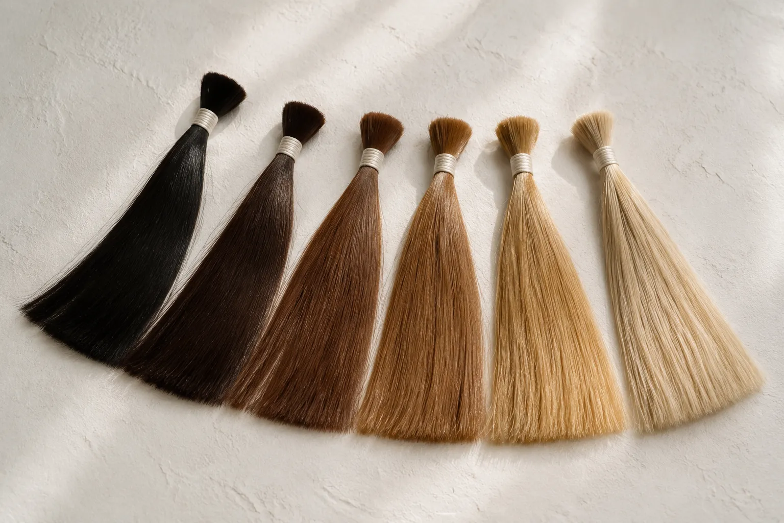 Six hair swatches fanned out, running from natural black through browns to light blonde